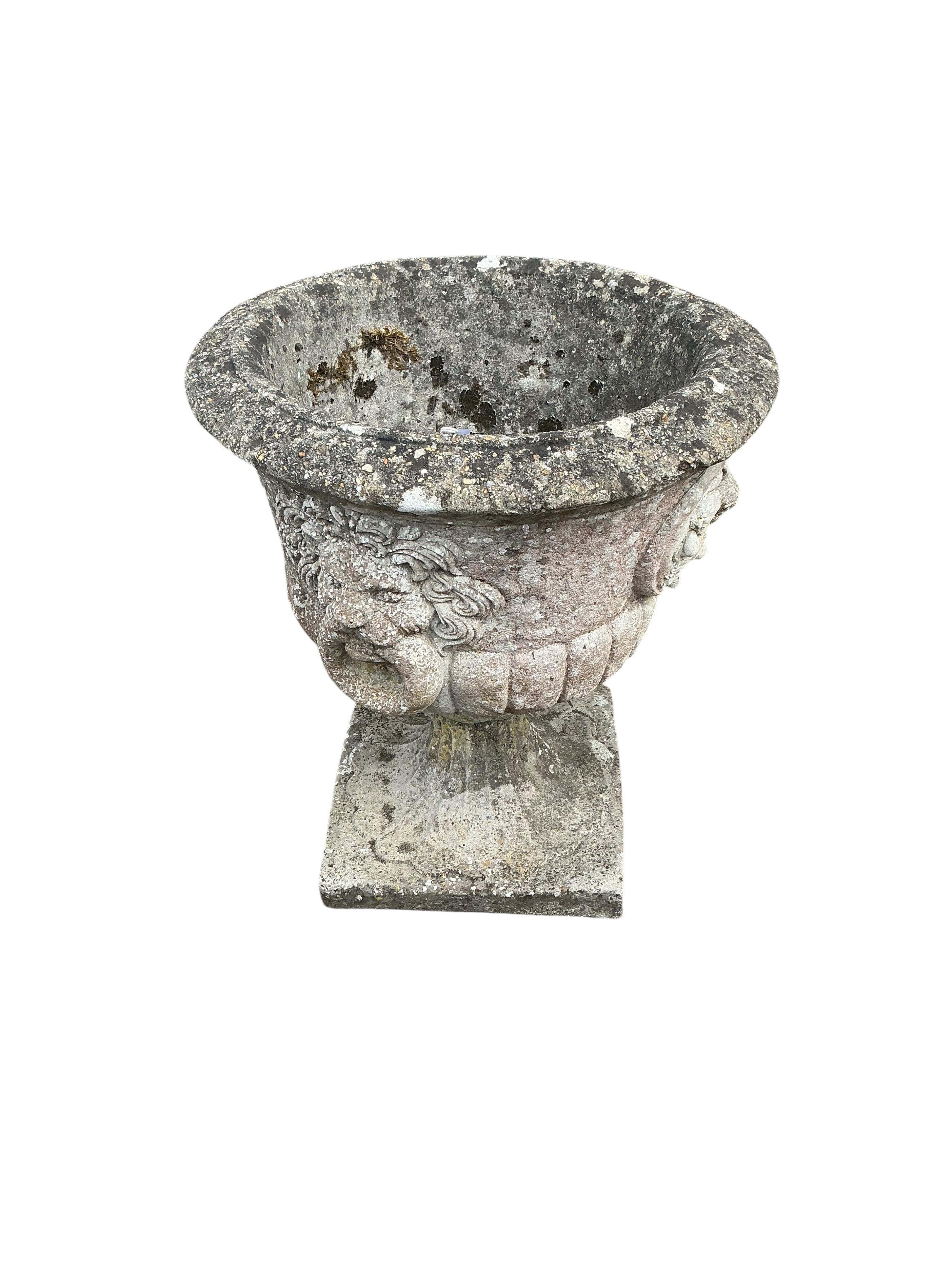A pair of circular reconstituted stone garden urns with moulded lion mask ring decoration, diameter 53cm, height 60cm